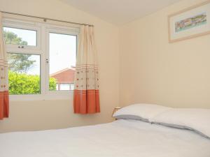 a bedroom with a bed and a window at Little Trebah in St Merryn