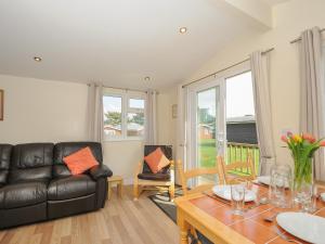 a living room with a black leather couch and a table at Little Trebah in St Merryn