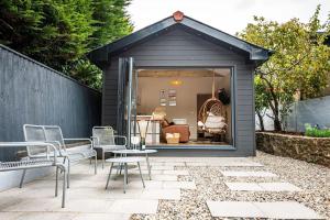 a black shed with chairs and a table at Gingerbread Lodge in Torquay