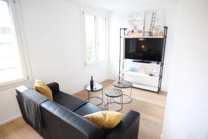 a living room with a black couch and a tv at Nest - Kanzleistrasse 217 in Zurich