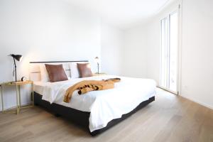 a white bedroom with a large bed with brown pillows at Nest - Kanzleistrasse 217 in Zurich