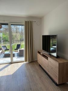 een woonkamer met een flatscreen-tv op een houten kast bij Apartament nad jeziorem in Pszczew