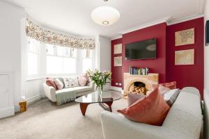 a living room with a red accent wall at Beautiful Edwardian Central Oxford home in Oxford