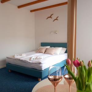 a bedroom with a bed and a table with wine glasses at Apartamenty Na Fali in Jastarnia