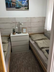 Una pequeña habitación con dos camas y una mesita de noche con una mesita de noche en Móra apartman 3., en Kiskunfélegyháza