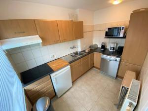 uma pequena cozinha com armários de madeira e electrodomésticos de aço inoxidável em Karen - 1st floor, Duinlaan 5b em Cadzand
