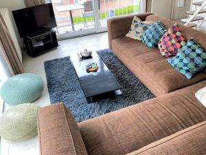 uma sala de estar com um sofá castanho e uma televisão em Karen - 1st floor, Duinlaan 5b em Cadzand