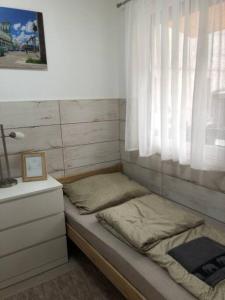 Cama pequeña en habitación con ventana en Móra apartman 3., en Kiskunfélegyháza