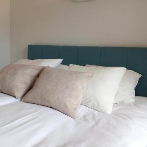 łóżko z białymi poduszkami i zielonym zagłówkiem w obiekcie Na Fali w Jastarni