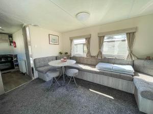 a living room with a couch and a table at Gorgeous Caravan With Decking In Breydon Water Holiday Park, Ref 10081b in Belton