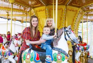 two women and a baby sitting on a carousel at Gorgeous Caravan With Decking In Breydon Water Holiday Park, Ref 10081b in Belton