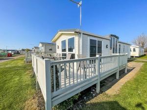 a mobile home with a porch and a white railing at Lovely 6 Berth Caravan With Decking At California Cliffs In Scratby Ref 50048l in Great Yarmouth