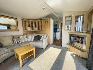 a living room with a couch and a table at Lovely 6 Berth Caravan With Decking At California Cliffs In Scratby Ref 50048l in Great Yarmouth