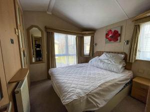 a bedroom with a bed and a large window at Lovely 6 Berth Caravan With Decking At California Cliffs In Scratby Ref 50048l in Great Yarmouth