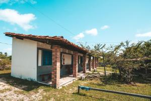 une petite maison blanche avec un toit rouge dans l'établissement Vila Capininga Ecopousada, à Santo Amaro