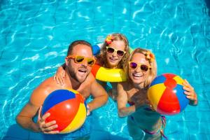 three people in a swimming pool holding beach balls at Beautiful Lodge With Decking At Breydon Water Park In Norfolk Ref 10022b in Belton