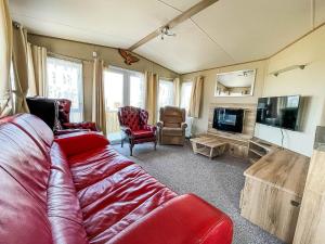 a living room with a red couch and a tv at Beautiful Caravan With Sea Views At California Cliffs In Scratby Ref 50010oc in Great Yarmouth