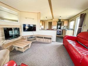 a living room with a red couch and a flat screen tv at Beautiful Caravan With Sea Views At California Cliffs In Scratby Ref 50010oc in Great Yarmouth