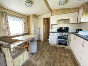 Lovely 8 Berth Caravan At Broadland Sands Near Great Yarmouth Ref 20161bs في Hopton on Sea: مطبخ صغير مع طاولة في القافلة