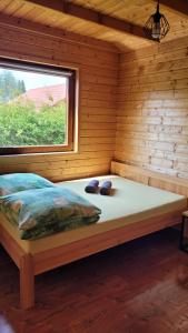 a bed in a log cabin with a window at Na Równej Bieszczady in Polańczyk