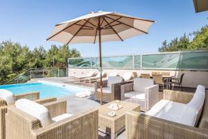 une terrasse avec un parasol, des chaises et une piscine dans l'établissement Deluxe Maisonette With Shared Pool 2#, à Anavyssos