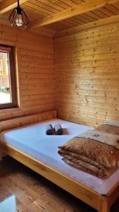 a bed in a wooden cabin with two slippers at Na Równej Bieszczady in Polańczyk
