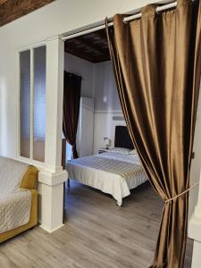 a bedroom with two beds and a curtain at Mansarde & Suite Maison 1706 Lago Orta in Borgomanero