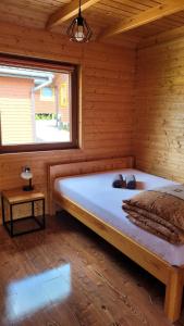 duże łóżko w drewnianym pokoju z oknem w obiekcie Na Równej Bieszczady w Polańczyku