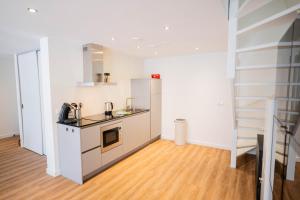 een keuken met witte muren en een houten vloer bij Exclusive 70m2 One-Bedroom Apartment in Tiel