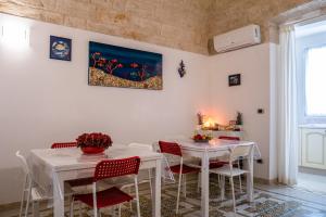 a dining room with white tables and red chairs at PESCIOLINO B&B in Mola di Bari