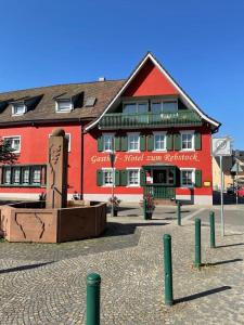 um edifício vermelho com uma estátua em frente em Gasthof Hotel zum Rebstock em Malterdingen