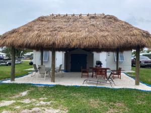 a hut with a table and chairs and a straw roof at Pet Friendly Half-Duplex, Cottage with 40' Slip Option at The Boat House Marina in Marathon