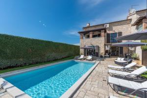 a pool with chairs and umbrellas next to a house at Villa Olea Mare with Private Heated Pool in Buici
