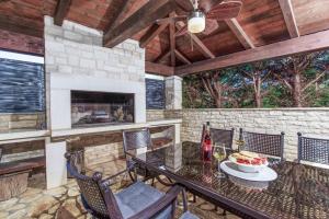 a patio with a table and chairs and a fireplace at Villa Olea Mare with Private Heated Pool in Buici