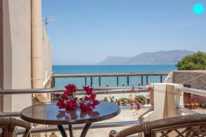 a table with flowers on a balcony with a view of the ocean at Akrogiali in Kissamos