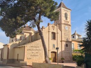 un edificio con una torre dell'orologio con un albero davanti di Calle Carlos Primero, Roda a Roda