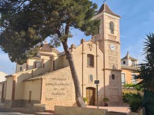a building with a clock tower with a tree in front at Calle Carlos Primero, Roda in Roda