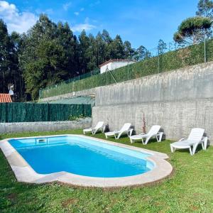 een zwembad met ligstoelen naast een muur bij Villa Lucerna in Pantín