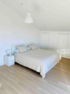 a bedroom with a large white bed and a wooden floor at Villa Lucerna, villa con piscina en Pantín in Pantín +31 photos