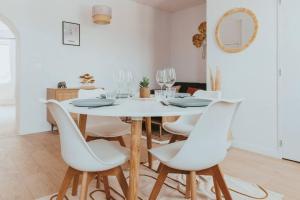 a white dining room with a white table and chairs at CAP VERT - Appartement Cocooning Chic in Saint-Étienne