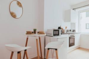 a white kitchen with a table and two white chairs at CAP VERT - Appartement Cocooning Chic in Saint-Étienne
