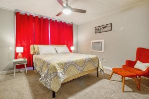 een slaapkamer met rode gordijnen en een bed en een rode stoel bij Cozy & Comfy - Few blocks away from Plaza District in Oklahoma City