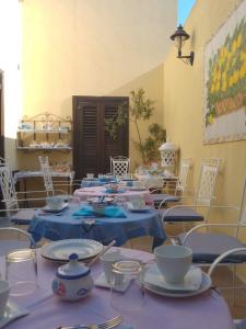 Pokój z niebieskimi stołami i krzesłami z naczyniami w obiekcie AFFITTACAMERE A TRE MINUTI IN SPIAGGIA Il Veliero w mieście San Vito lo Capo
