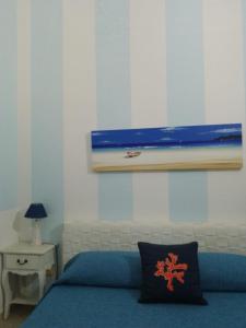 a bedroom with a blue bed and a picture on the wall at AFFITTACAMERE A TRE MINUTI IN SPIAGGIA Il Veliero in San Vito lo Capo