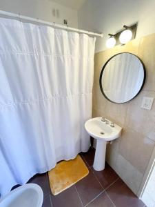 La salle de bains est pourvue d'un rideau de douche blanc et d'un lavabo. dans l'établissement Saavedra 118 3°J by depptö, à Bahía Blanca