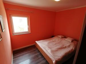 a bedroom with orange walls and a bed and a window at Splendid Sea View Apartment Marko in Novalja