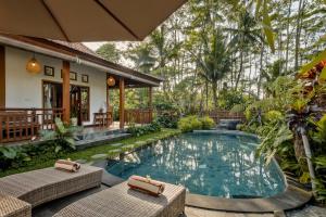 Una piscina al aire libre con dos sillas y una casa. en Ratni Ubud Villa, en Ubud