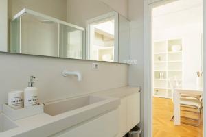 uma casa de banho branca com um lavatório e um espelho em Bilocale vista sul Duomo di Milano em Milão