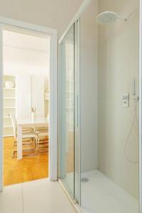 uma porta de duche em vidro num quarto branco com uma mesa em Bilocale vista sul Duomo di Milano em Milão
