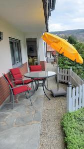 een patio met een tafel en stoelen en een parasol bij Ferienwohnung Haus Sommerberg in Leonhardshof